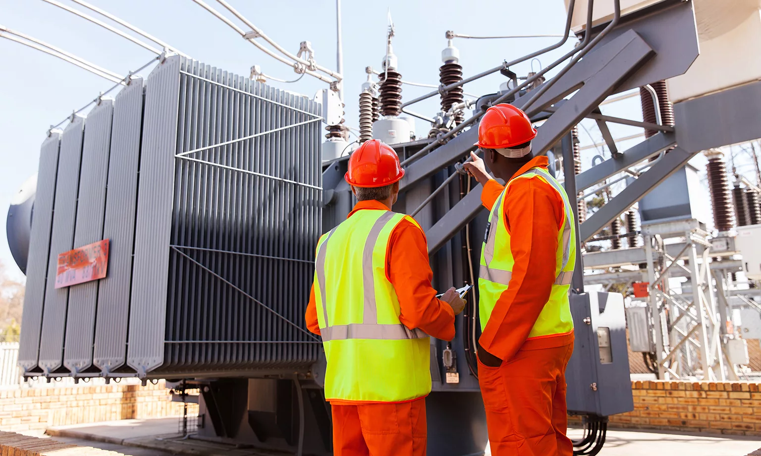 electricians standing next to a transformer