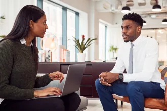 Businesswoman Interviewing Male Job Candidate In Seating Area Of Modern Office